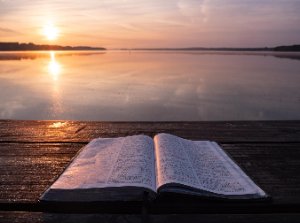 "Book On Top Of Table and Body of Water," Photo by Aaron Burden on Unsplash