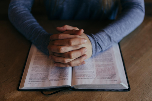 "Man Holding Hands on Open Book" by Patrick Fore on Unsplash